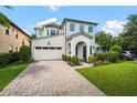 Elegant white brick home featuring an attached garage, lush lawn, and a welcoming paved driveway at 528 Greely St, Orlando, FL 32804
