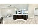Kitchen island with breakfast bar, dark cabinets, and a view of living spaces at 6449 Sw 180Th Cir, Dunnellon, FL 34432