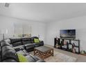 A living room featuring a black leather sofa and a television at 7344 Swallow Run # 7344, Winter Park, FL 32792