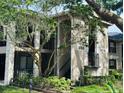 Exterior view of a two-story home with balconies, mature trees, and lush landscaping at 1055 Kensington Park Dr # 205, Altamonte Springs, FL 32714