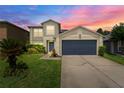 Charming two-story home featuring well-manicured lawn and a gray two-car garage door with a sunset at 1224 Blackwater Pond Dr, Orlando, FL 32828