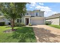 Charming two-story home showcasing a brick driveway, attached two-car garage, and landscaped front yard at 1292 Cavender Creek Rd, Minneola, FL 34715