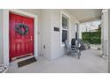 Stylish red front door adorned with a wreath, complemented by seating and the home's address number at 2345 Volunteer Ave, Kissimmee, FL 34744