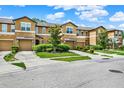 View of multiple townhomes with attached garages, green lawns, and landscaped front yards at 2508 Seven Oaks Dr, St Cloud, FL 34772