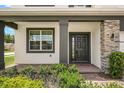 Close-up showcasing a front door with black trim, brick entrance, column, side-window, and manicured bushes at 2541 Leyland Cypress Ln, Sanford, FL 32773