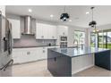 Modern kitchen featuring stainless steel appliances, white cabinetry, a large island and stylish pendant lighting at 2541 Leyland Cypress Ln, Sanford, FL 32773