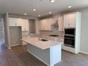 Modern kitchen features white cabinetry, a center island, and stainless steel appliances at 441 Lady Palm St, Apopka, FL 32703