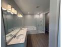 Bathroom with dual vanities, a soaking tub, and separate glass-enclosed shower at 441 Lady Palm St, Apopka, FL 32703