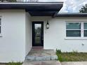Close-up of the front entrance with a black door, lantern, and textured white siding at 4732 Luce Rd, Lakeland, FL 33813