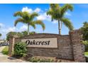 Welcoming community sign with lush landscaping and mature palm trees on a sunny day at 509 Cresting Oak Cir # 73, Orlando, FL 32824