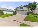 Home featuring an expansive driveway, two-car garage, and a lush green lawn at 5703 Arnold Zlotoff Dr, Orlando, FL 32821