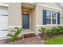 Inviting front entrance featuring a stylish blue front door, brick pathway, and colorful landscaping at 5808 Arboretum St, St Cloud, FL 34771