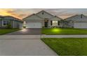 Dusk view of home with a brick driveway, well-kept lawn, and a charming facade at 5808 Arboretum St, St Cloud, FL 34771