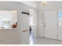Bright entryway with white tile flooring, coat hooks, and a glimpse into other rooms of the home at 630 Park Valley Cir, Minneola, FL 34715