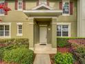 Up-close view of the welcoming front entrance, featuring green columns and colorful landscaping at 7462 Bentonshire Ave, Windermere, FL 34786