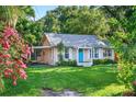Charming single-story home with a bright blue front door, carport, and large front lawn at 815 E 11Th Ave, Mount Dora, FL 32757