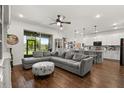 Open-concept living room with a gray sectional sofa, wood-look flooring, and a view of the kitchen and backyard at 922 Grazie Loop, Davenport, FL 33837