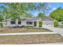 Well-maintained single-story home featuring a landscaped front yard, mature shade tree, and an attached two-car garage at 107 Hilltop Dr, Longwood, FL 32750