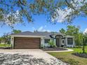 Charming home features a modern exterior with manicured lawn and a wood-look garage door at 13735 Sw 73Rd St, Ocala, FL 34481