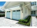 Close-up of the attached two-car garage with blue doors and elegant brick paver driveway and manicured landscape at 1820 Glencoe Rd, Winter Park, FL 32789