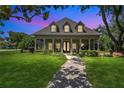 Stunning single-Gathering home with a beautiful manicured lawn, inviting porch, and mature trees under a colorful sky at 19554 Spring Oak Dr, Eustis, FL 32736
