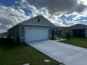 Attractive one-story home showcases a two-car garage, a long concrete driveway, and verdant lawn at 1982 King Ranch St, Kissimmee, FL 34744