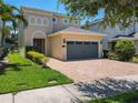 Inviting home exterior featuring a paver driveway, a two-car garage, and manicured landscaping at 370 Pendant Ct, Kissimmee, FL 34747