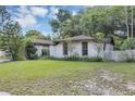 View of the front yard and the home with a brown roof and lush surrounding greenery at 380 Violet Dell Dr, Casselberry, FL 32707