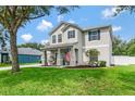 Charming two-story home with a well-manicured lawn, blue shutters, and inviting front porch with comfortable seating at 486 Shirley Dr, Apopka, FL 32712
