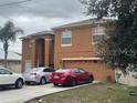 Two-story tan home with an attached two-car garage and driveway parking at 547 Big Sioux Ct, Kissimmee, FL 34759