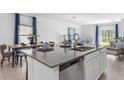 Well-lit kitchen includes an island with a stainless steel sink and a dishwasher, connecting seamlessly to the dining and living areas at 5687 Portico Pl, Kissimmee, FL 34758