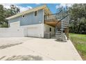View of back exterior with a white brick foundation, spiral staircase, and two car garage at 5836 Spruce Creek Woods Dr, Port Orange, FL 32127