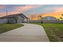 Beautiful one-story home with an extended driveway and neutral-colored exterior at sunset at 785 Orchid Grove Blvd, Davenport, FL 33837