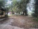 Expansive backyard with mature trees and a glimpse of a community pool in the distance at 4250 Lake Ave, Kissimmee, FL 34746