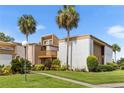 Condo exterior with manicured landscaping and palm trees against a blue sky at 1051 S Highland St # 7D, Mount Dora, FL 32757