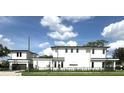 Modern home exterior featuring clean lines, white facade, and black trim, complemented by a lush green lawn at 1733 Harmon Ave, Winter Park, FL 32789