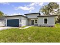 Exterior view of the home featuring a well-manicured lawn, a blue garage door, and a charming gray exterior at 4345 Sw 143Rd Lane Rd, Ocala, FL 34473