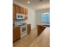 Modern kitchen with wooden cabinets, granite countertops, and a large window at 512 Novara Way, Davenport, FL 33837
