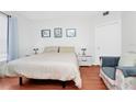 Cozy bedroom with a comfortable bed, wood floors, and a sitting area with a modern chair at 5566 Metrowest Blvd # 10, Orlando, FL 32811