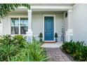 Charming entrance with blue front door, decorative plants and covered porch at 609 Big Pine Ave, Minneola, FL 34715