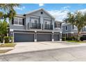 Townhome featuring a gray exterior, multiple garage doors, and quaint second-story balconies with lush green trees at 6484 S Goldenrod Rd # 41A, Orlando, FL 32822