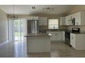 Well-lit kitchen with stainless steel appliances, granite countertops, white cabinets and island at 739 Parrot Ct, Poinciana, FL 34759