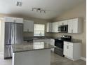 Well-lit kitchen with stainless steel appliances, granite countertops, white cabinets and island at 739 Parrot Ct, Poinciana, FL 34759