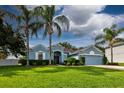 Charming blue home boasts a well-manicured lawn, lush landscaping, and swaying palm trees at 2237 Wintermere Pointe Dr, Winter Garden, FL 34787