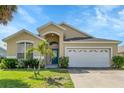Inviting home featuring a well-maintained lawn, mature landscaping, and an attached two-car garage at 2546 Oneida Loop, Kissimmee, FL 34747