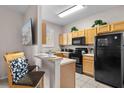 Functional kitchen featuring oak cabinets, black appliances, and a bar area with stools for casual dining at 2717 Camaro Dr, Kissimmee, FL 34746
