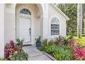 Close-up of the front door with an arched entry and manicured landscaping featuring colorful plants and pathway lighting at 3706 Andover Cay Blvd, Orlando, FL 32825