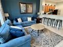 Cozy living room with comfortable blue seating, modern decor, and an open layout to the kitchen at 7682 Sir Kaufmann Ct, Kissimmee, FL 34747