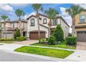 Stunning two-story home featuring a brown garage door, tile roofing, landscaped yard, and elegant palm trees at 8912 Rhodes St, Kissimmee, FL 34747
