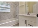 Bright bathroom with white marble tile surround, shower and bath combination, and a white vanity at 1065 Universal Rest Pl, Kissimmee, FL 34744